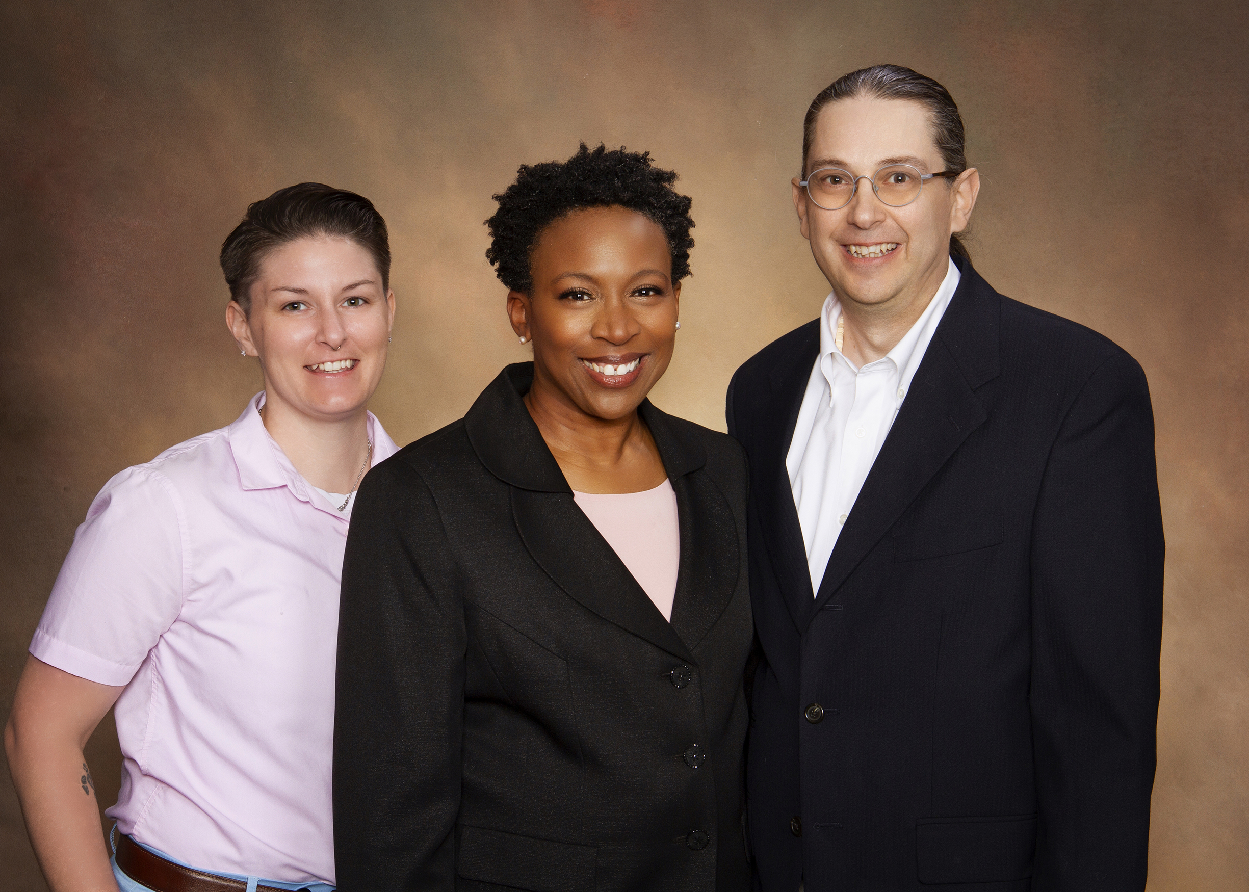 Dr. Adrienne Robertson, Timothy Hook LCSW, and Hannah Veit smile together in a professional team portrait, representing the compassionate, collaborative care team at Abundant Health & Wellness